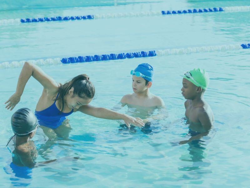 View of some kids playing in a pool during a swim lesson