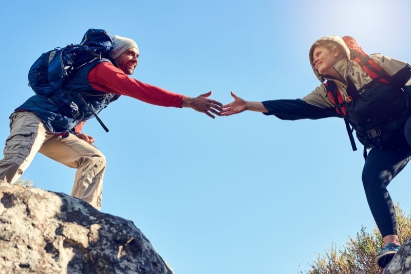 people on hill reaching out in trust
