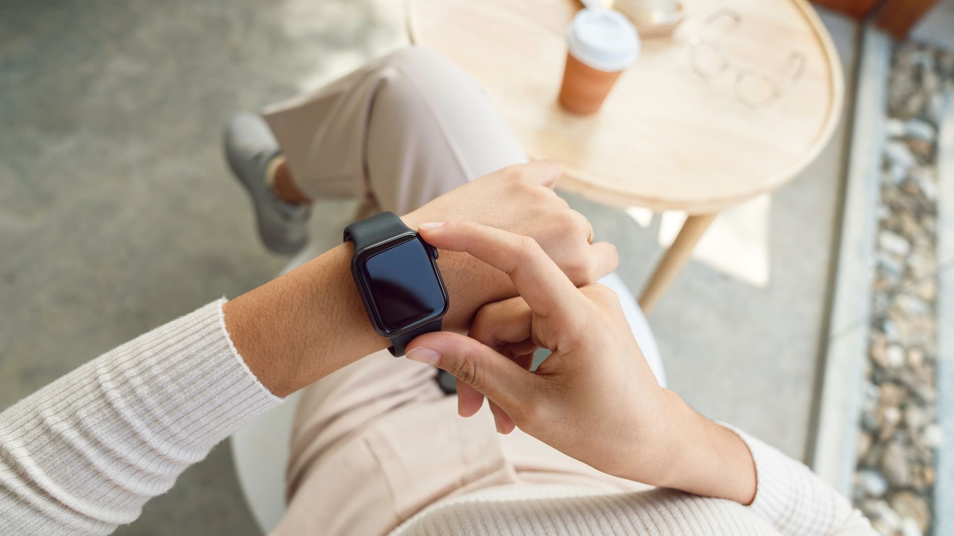 Woman at coffee table with Apple style watch on wrist