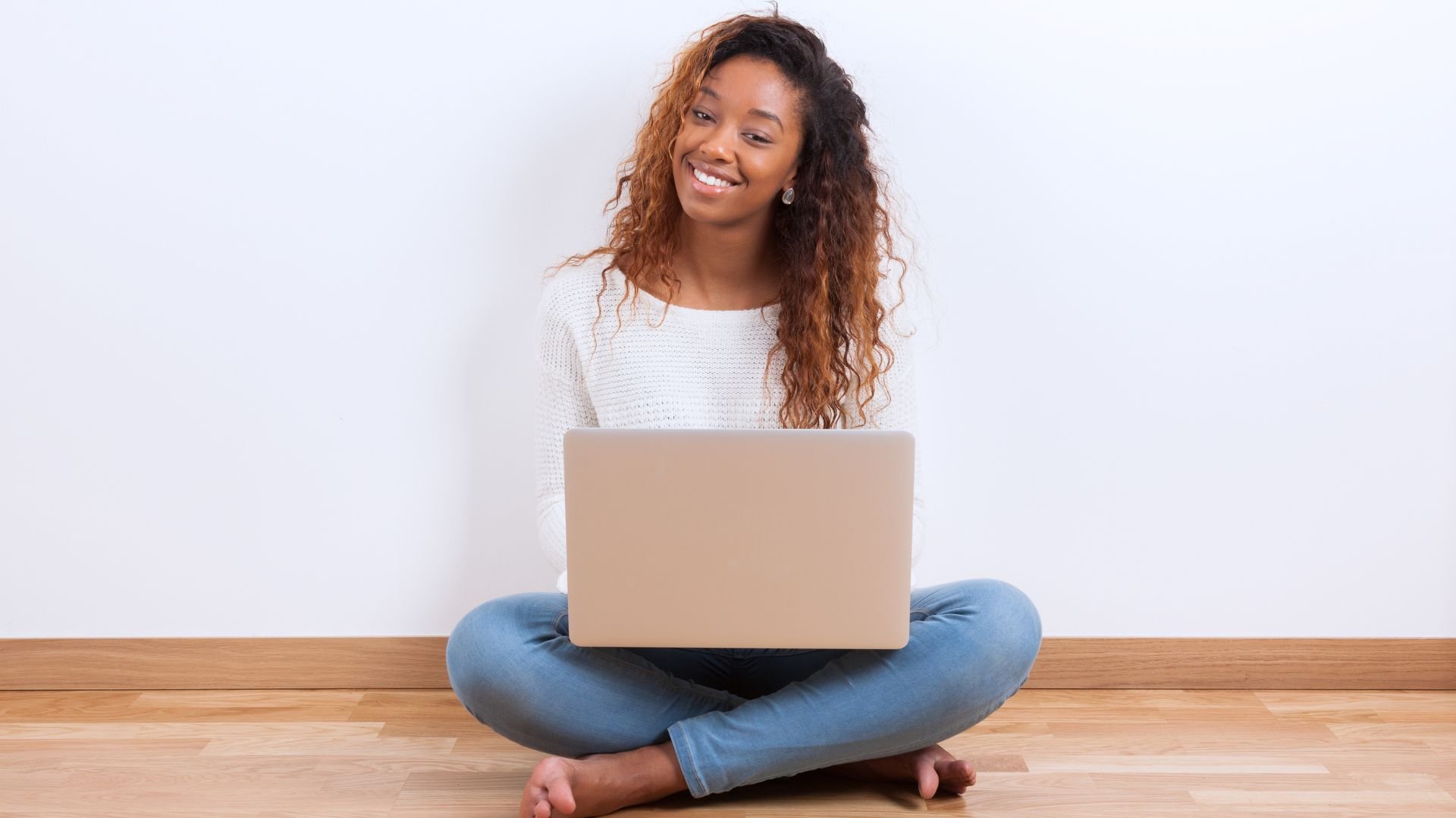 Woman sitting on the floor with laptop smiling